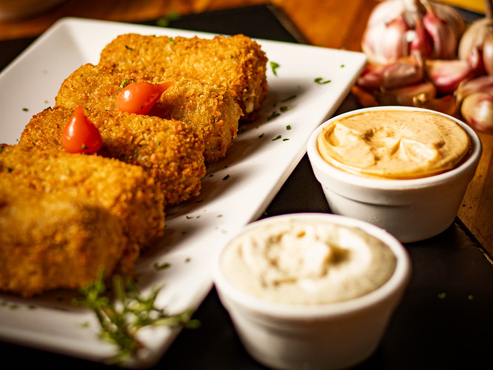 Croquetas emplatadas con alioli, salsa brava y ajos